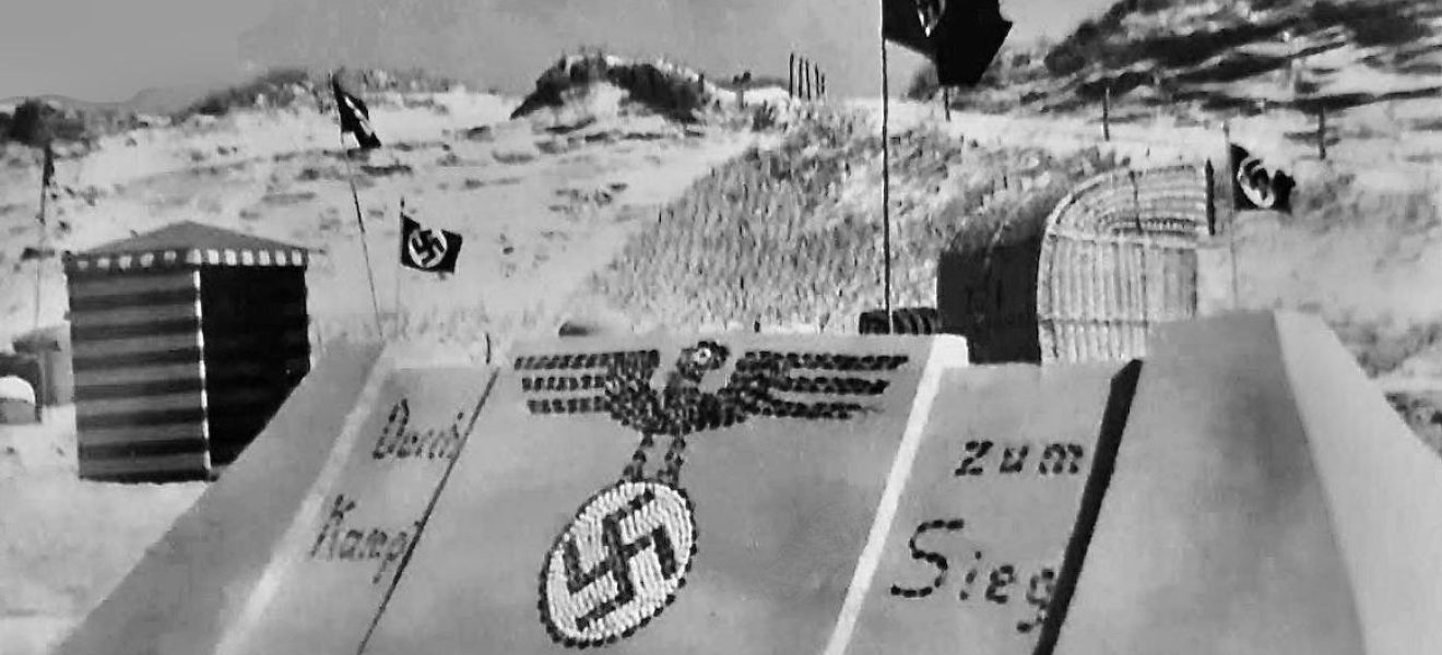 Sandburg auf Langeoog mit nationalsozialistischer Parolen und NS-Symbol aus Muscheln sowie Hakenkreuzflaggen